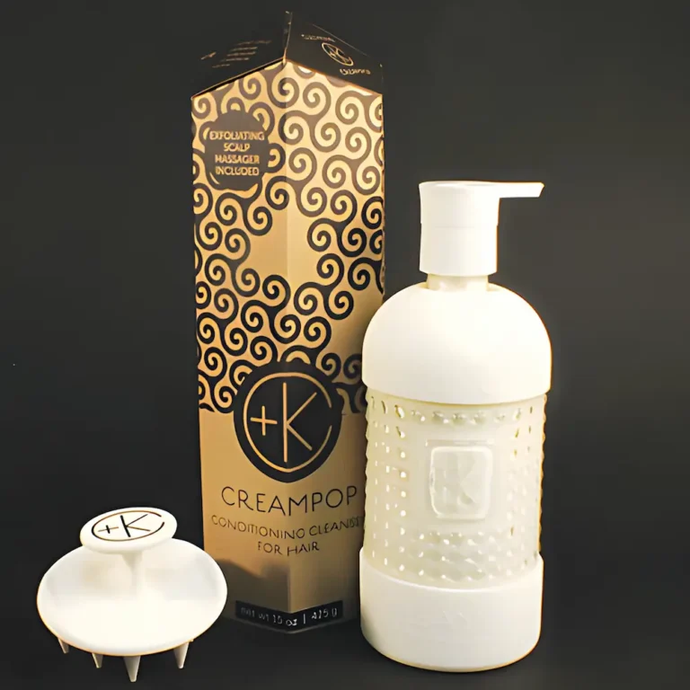 a black background with a white scalp brush, a white glass bottle with white product inside a pump bottle. there is a cardboard obelisk showing its packaging.