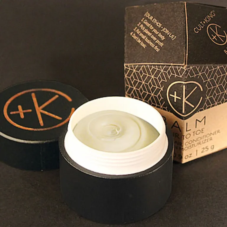 a black bamboo jar with a white cream shows a super smooth balm with the c+k logo on the lid and the sacred geometry obelisk cardboard packaging we love.