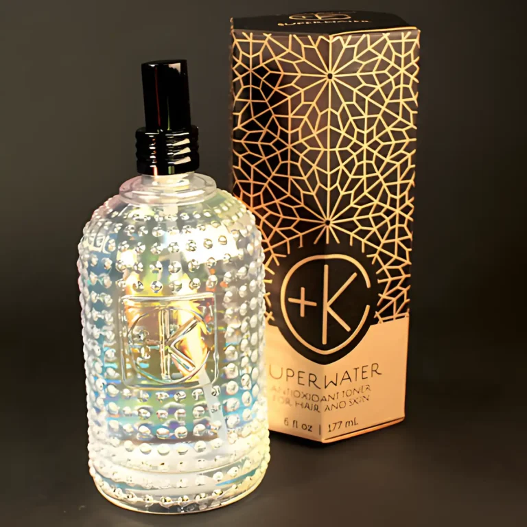 a beautiful holographic glass botle with lil bead balls on the outside and a black lid sits in front of a sacred geometry decorated cardboard obelisk box packaging.