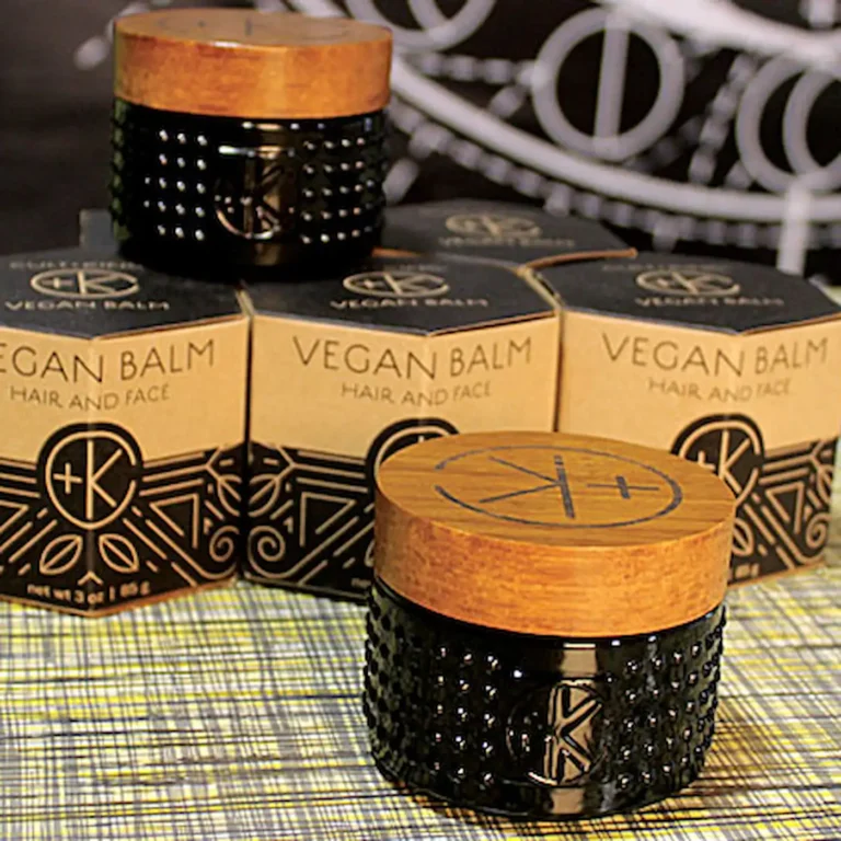 a cute tiny black glass jar with a bamboo like and a black c+k logo. there are geometric cardboard boxes behind it and another lil jar.