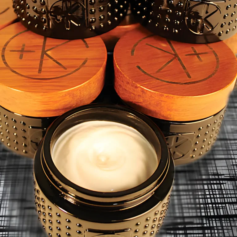 a black glass jar shows a smooth white balm and behind it are other jars with their bamboo lids and the c+k logo.