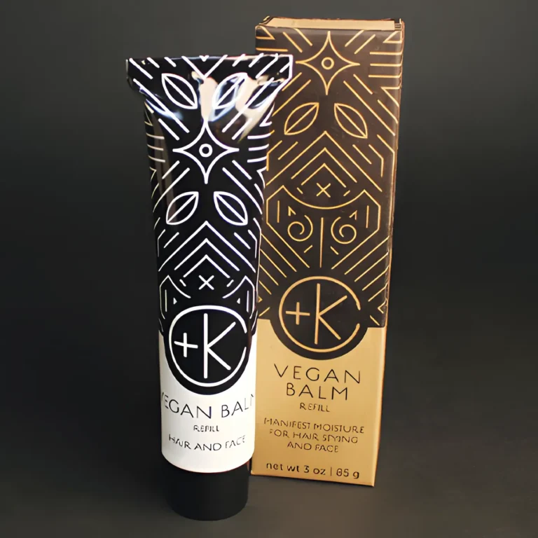 a white aluminum tube with black writing ad a black lid on a black background. there is a cardboard box packaging behind it that matches it's label.