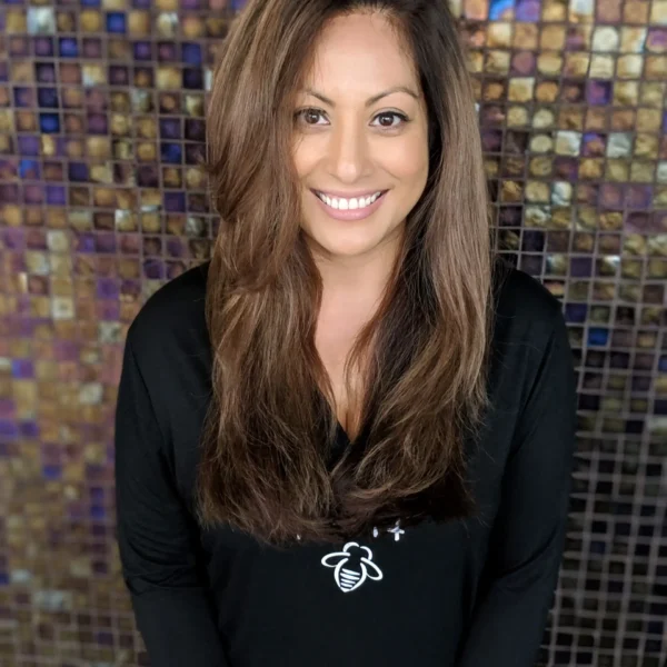 a woman with grey coverage and caramel brunette highlights and balayage stands in front of a mosaic background