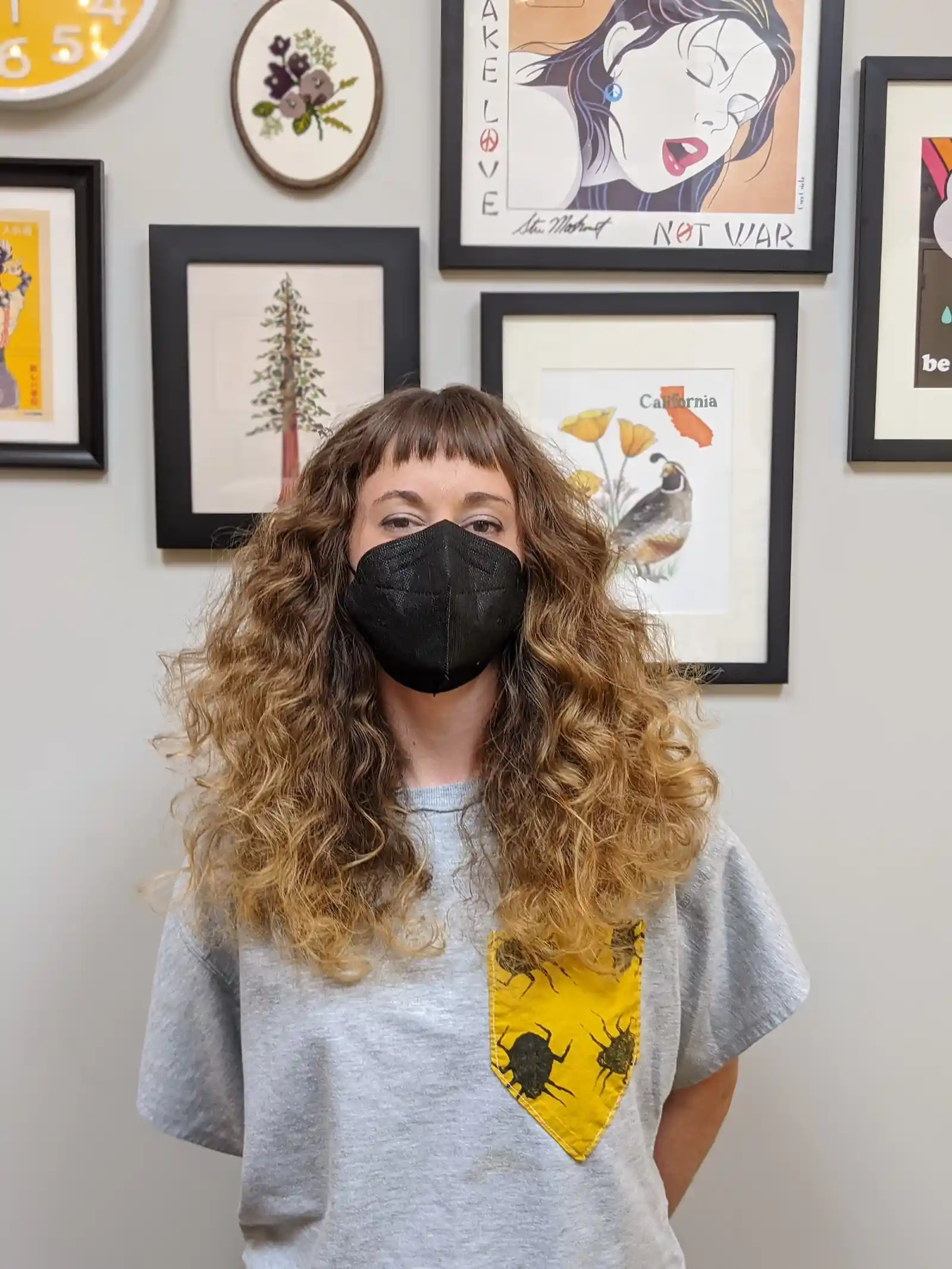 Long curly haircut with natural volume and textured fringe, brunette with golden highlights, front view.