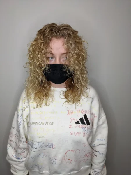 Shoulder-length curly haircut with blonde balayage and defined natural texture, front view.