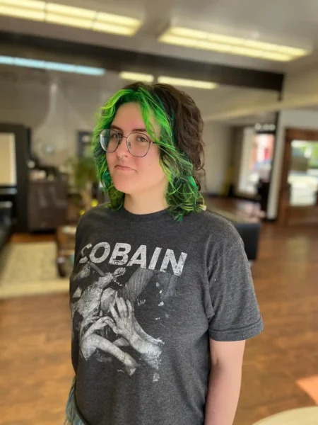 Medium shag haircut with vivid green highlights and dark brunette base, front angle view.