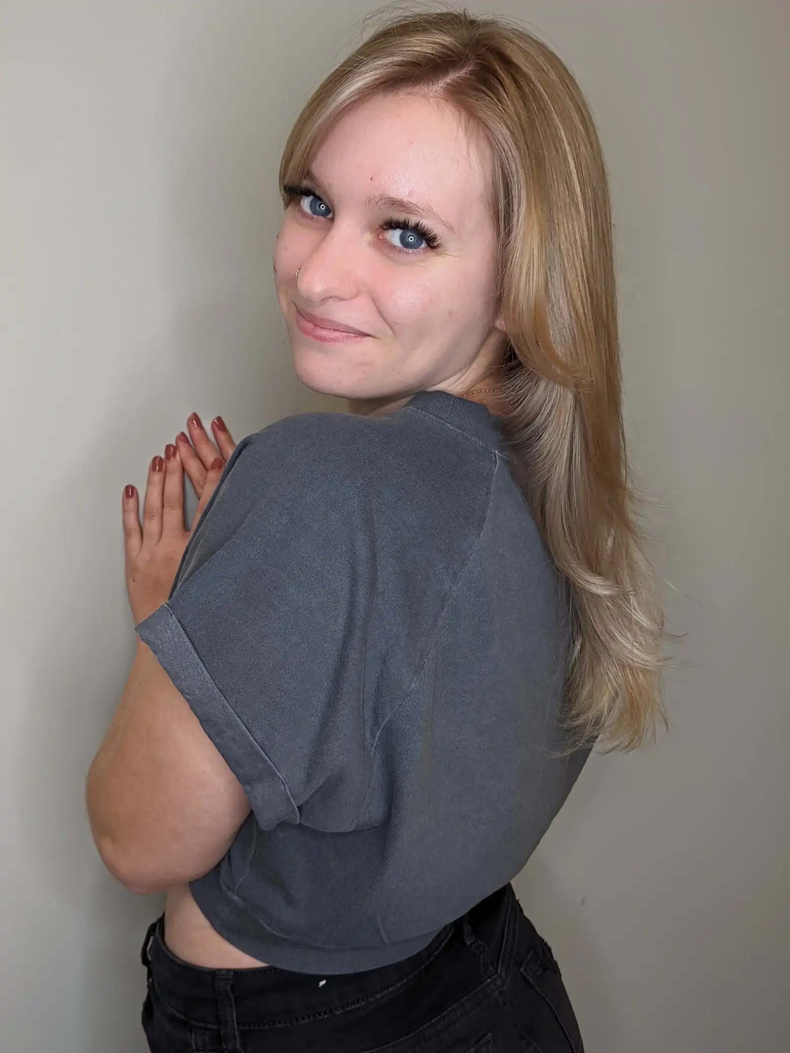 Warm blonde long-layer haircut with face-framing and soft blowout, back three-quarter view.