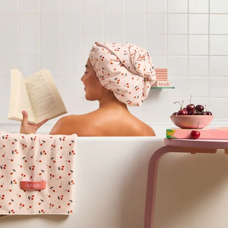 a woman in a bathtub reads a bookin a satin lined cherry print showercap