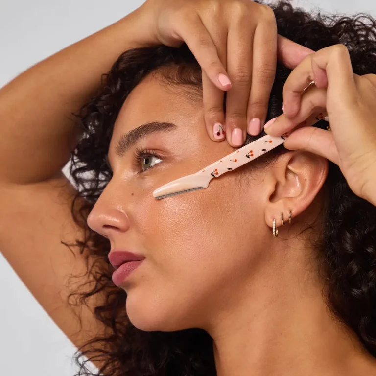 a woman dermaplanes her face with a kitsch cherry dermaplaner blade