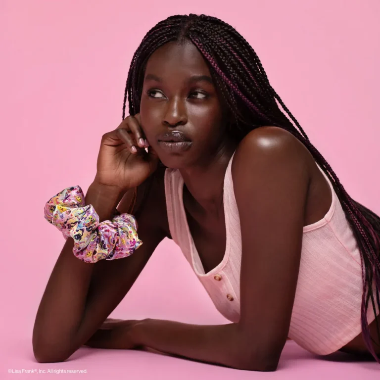 wearing a giant lisa frank scrunchie on her wrist, a woman ponders into the distance