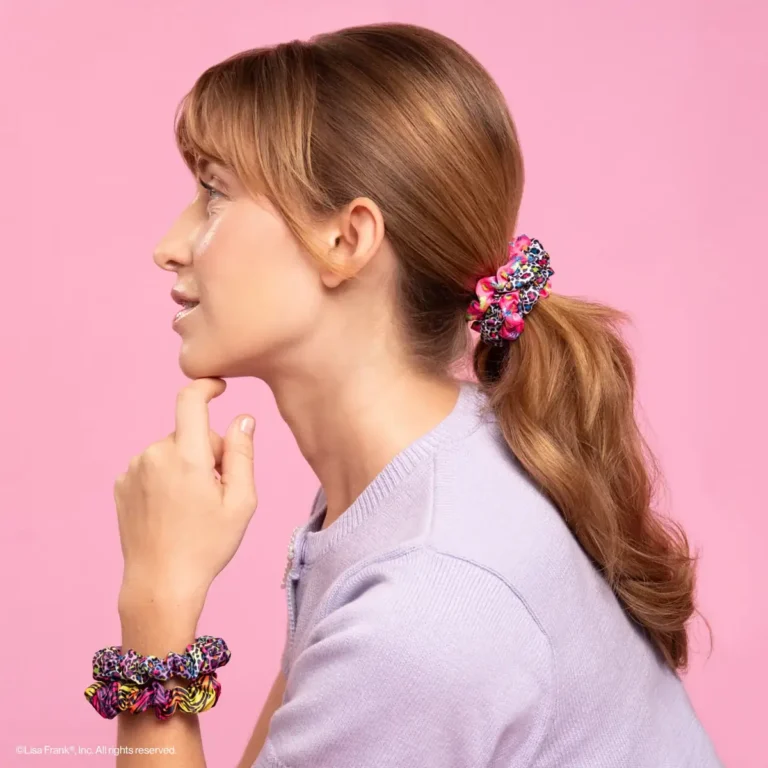 a profile of a woman wearing a ruched scrunchie in her hair and on her wrists with a pink background