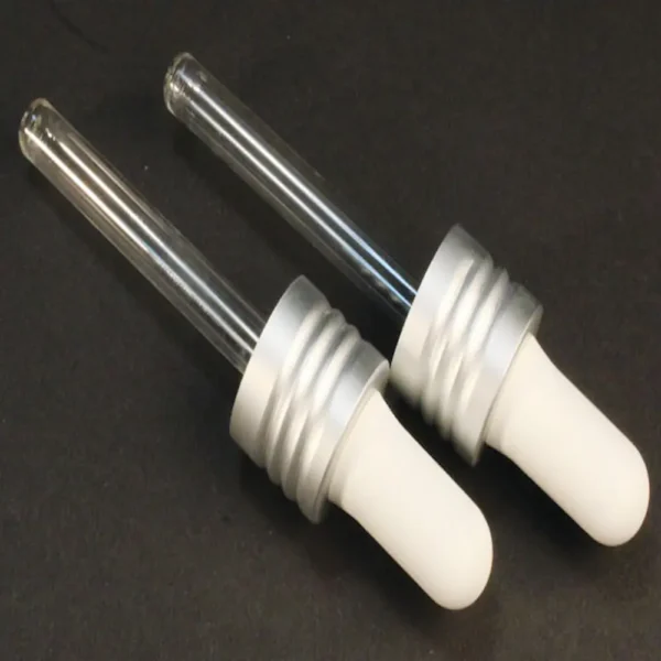 2 replacement glass droppers for mini jelly from cult + king on a black background. the rubber squeezer on top is white and the glass is clear.