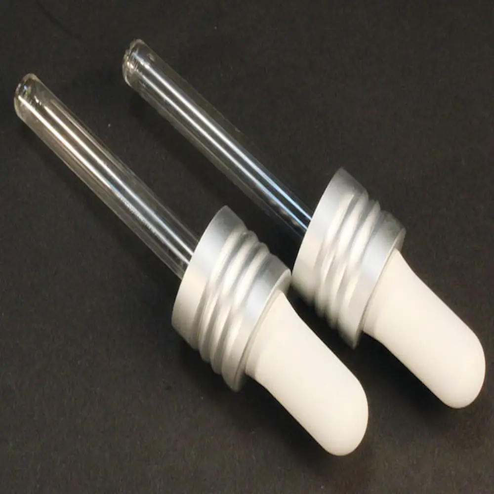 2 replacement glass droppers for mini jelly from cult + king on a black background. the rubber squeezer on top is white and the glass is clear.