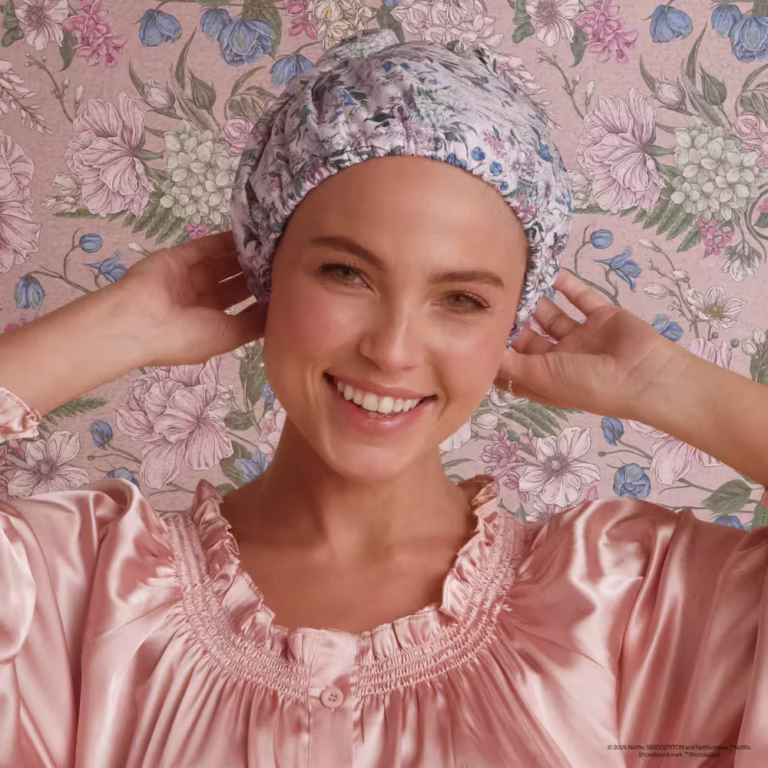 a womain wears the flexi cap satin lined shower cap in wisteria from the kitsch x bridgerton collection