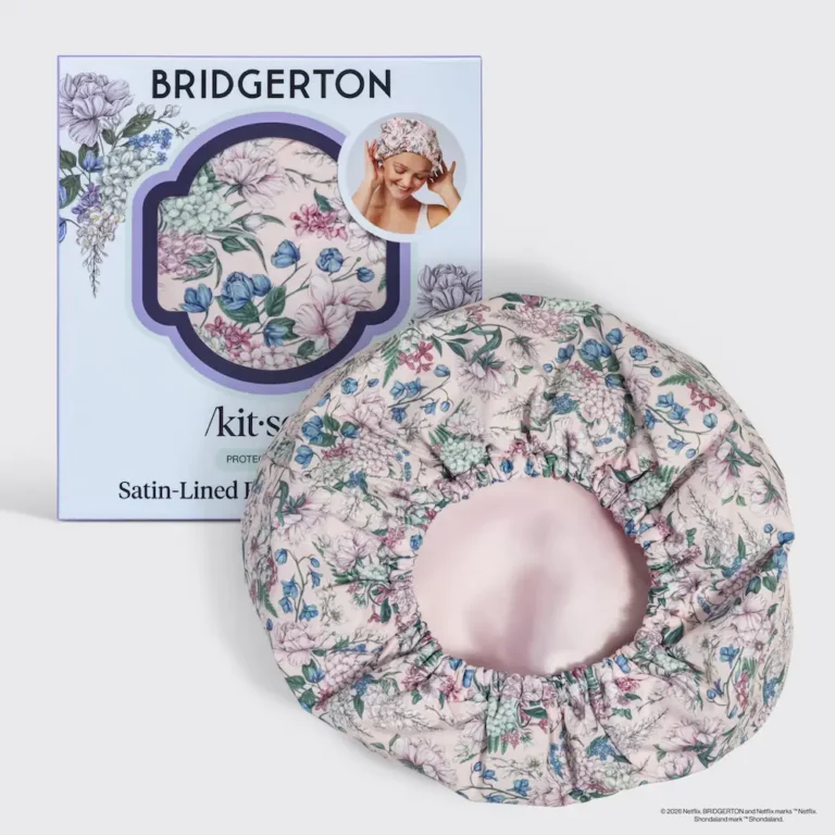 the bridgerton wisteria flexi cap satin lined shower cap from kitsch sits in front of it's packaging displaying it's beautiful blues floral pattern and blush satin lining.