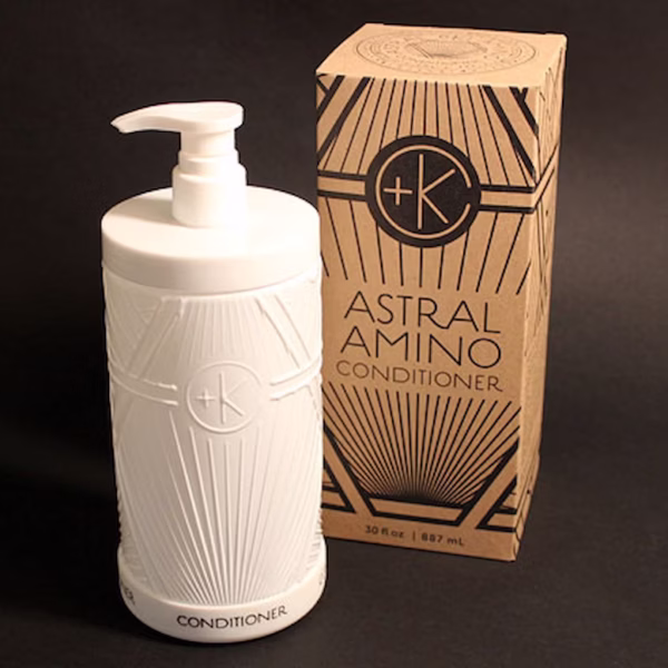 a solid white glass bottle that is refilable nex to the astral amino conditioner cardboard recyclable box.