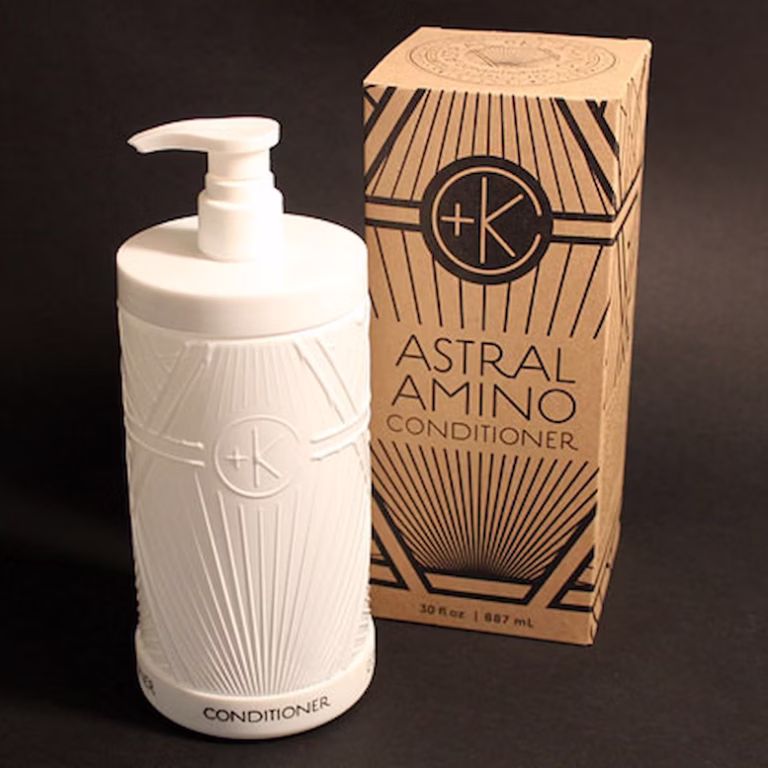 a solid white glass bottle that is refilable nex to the astral amino conditioner cardboard recyclable box.