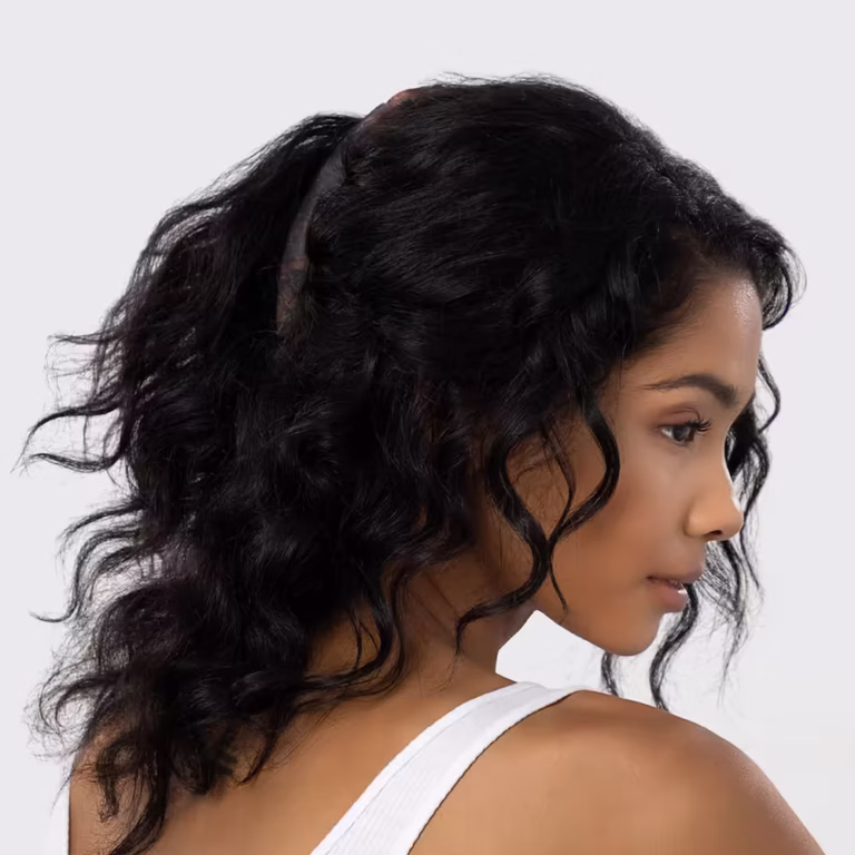 Woman with long, curly black hair styled in a half-up ponytail