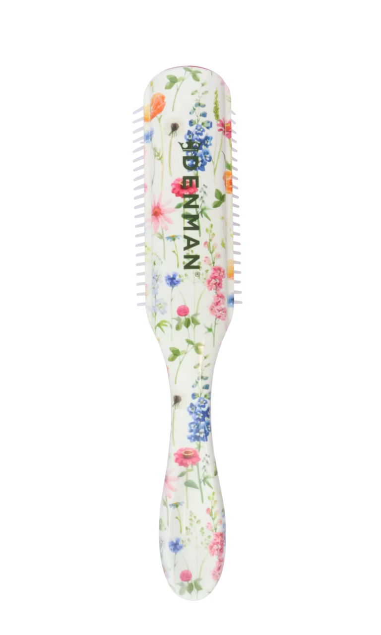Back view of the Denman D3 Deluxe Floral Fantasies styling brush featuring a white handle decorated with a vibrant, colorful wildflower pattern and a dark green Denman logo.